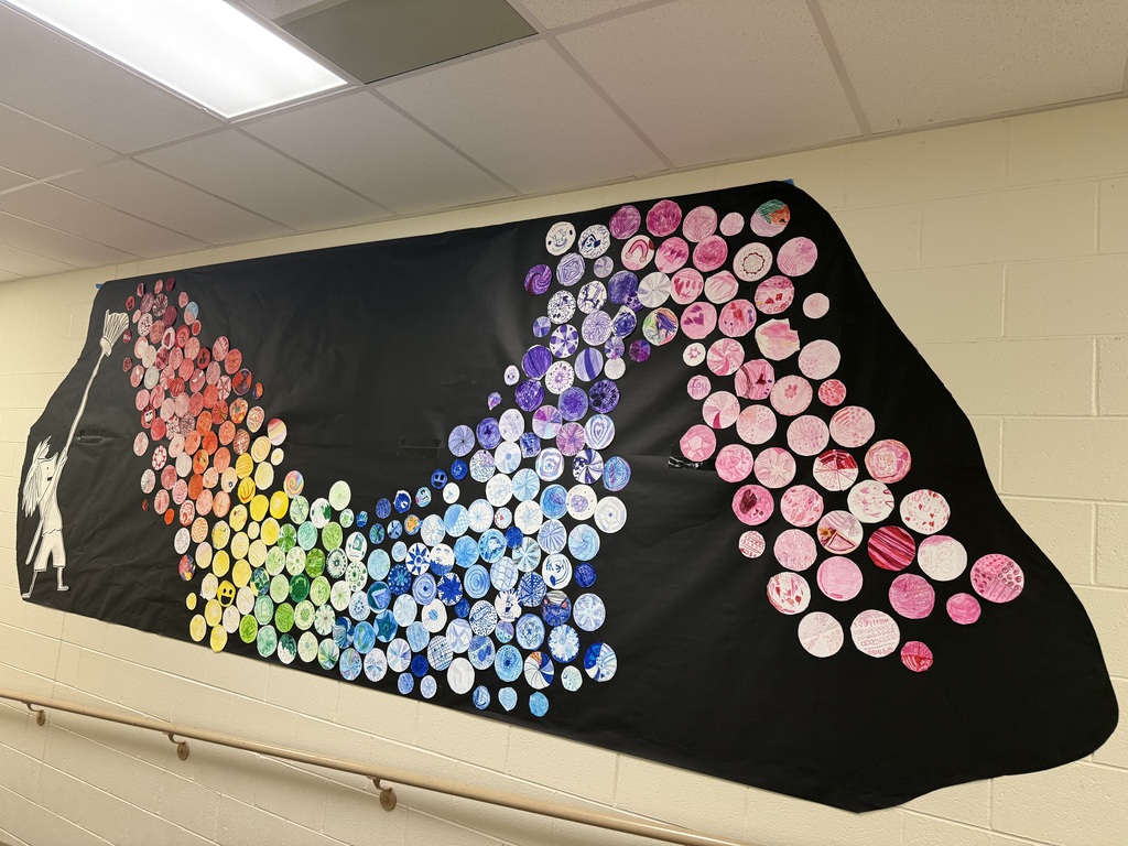 girl holding paint brush with a wave of colorful dots on a black paper