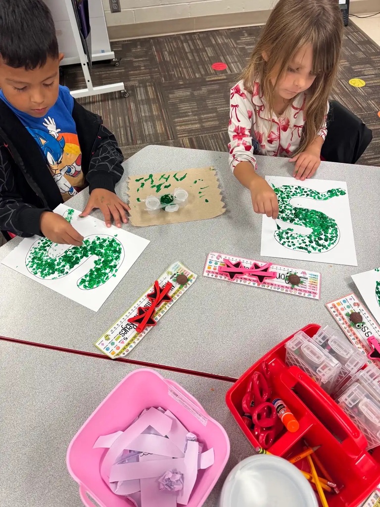 2 students sitting at a table making green dots in a snake outline