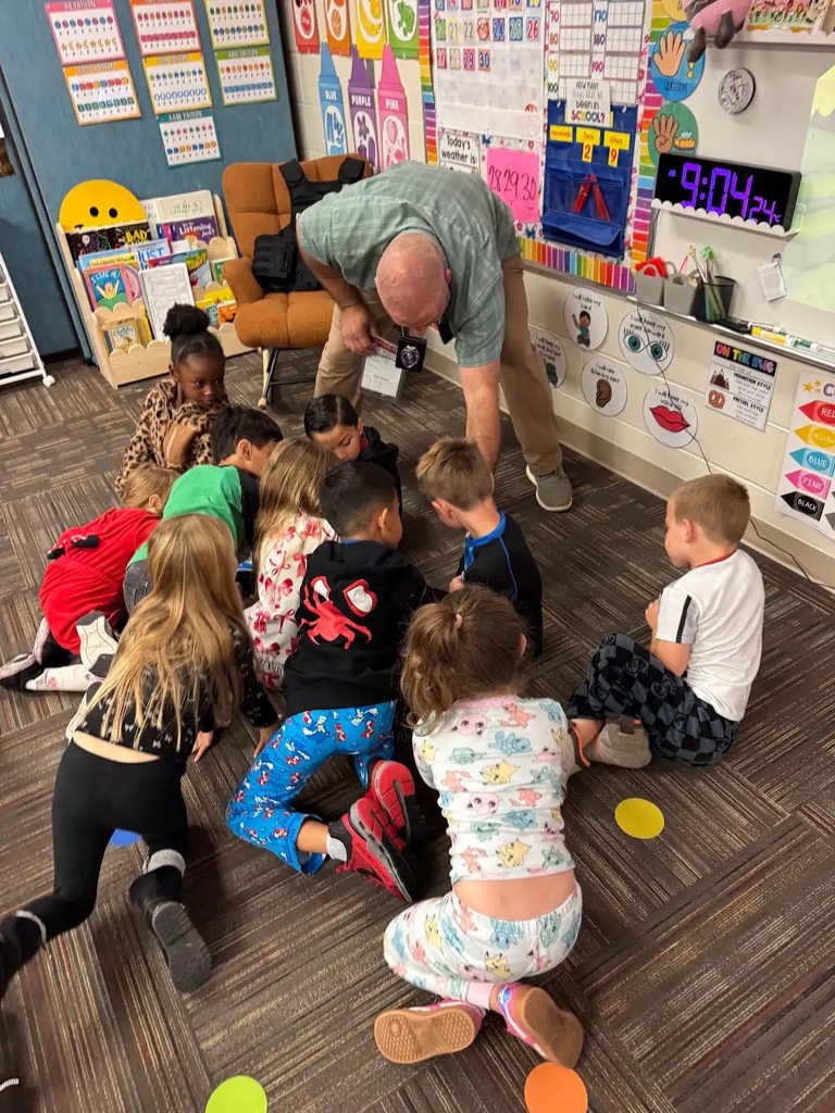 man bending down in front of a group of children. Children gathering around him