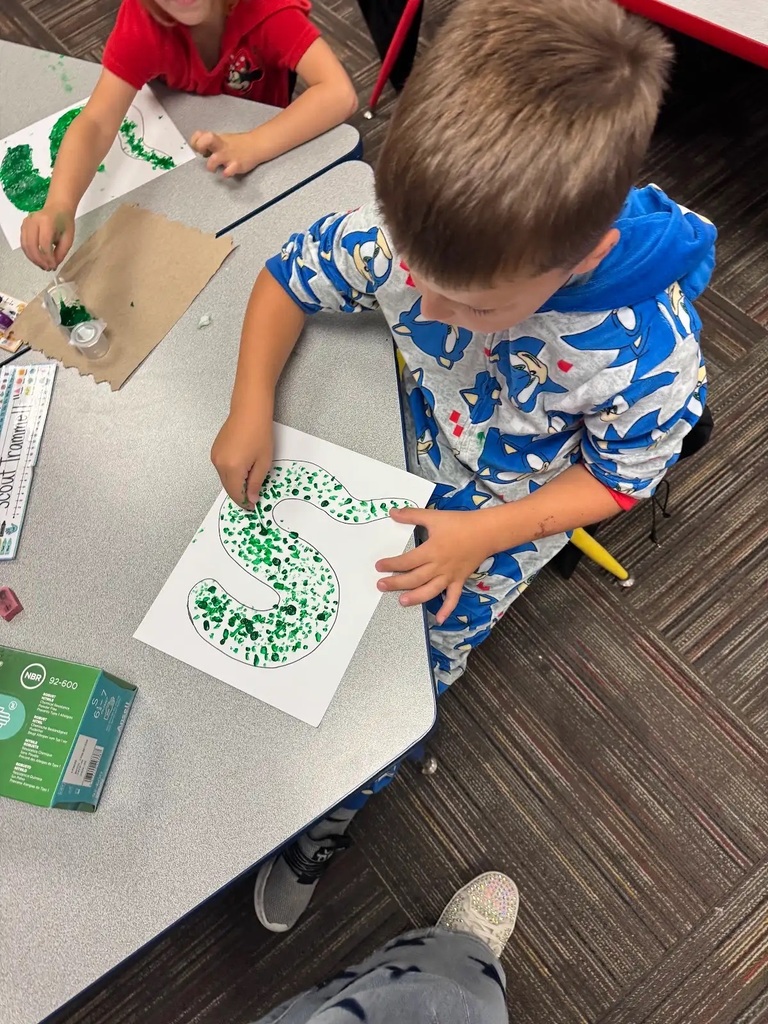 student sitting at table making dots to inside of a snack outline