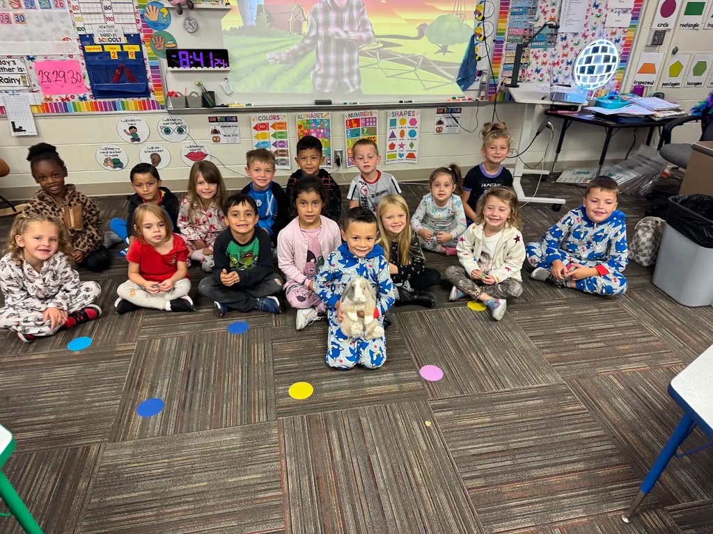 group of students sitting on floor looking at camera. student in front holding a bunny