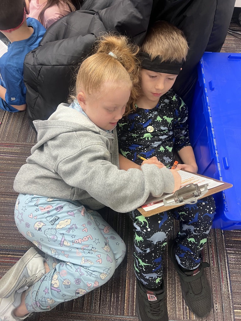two students with a clipboard laying on the floor doing math