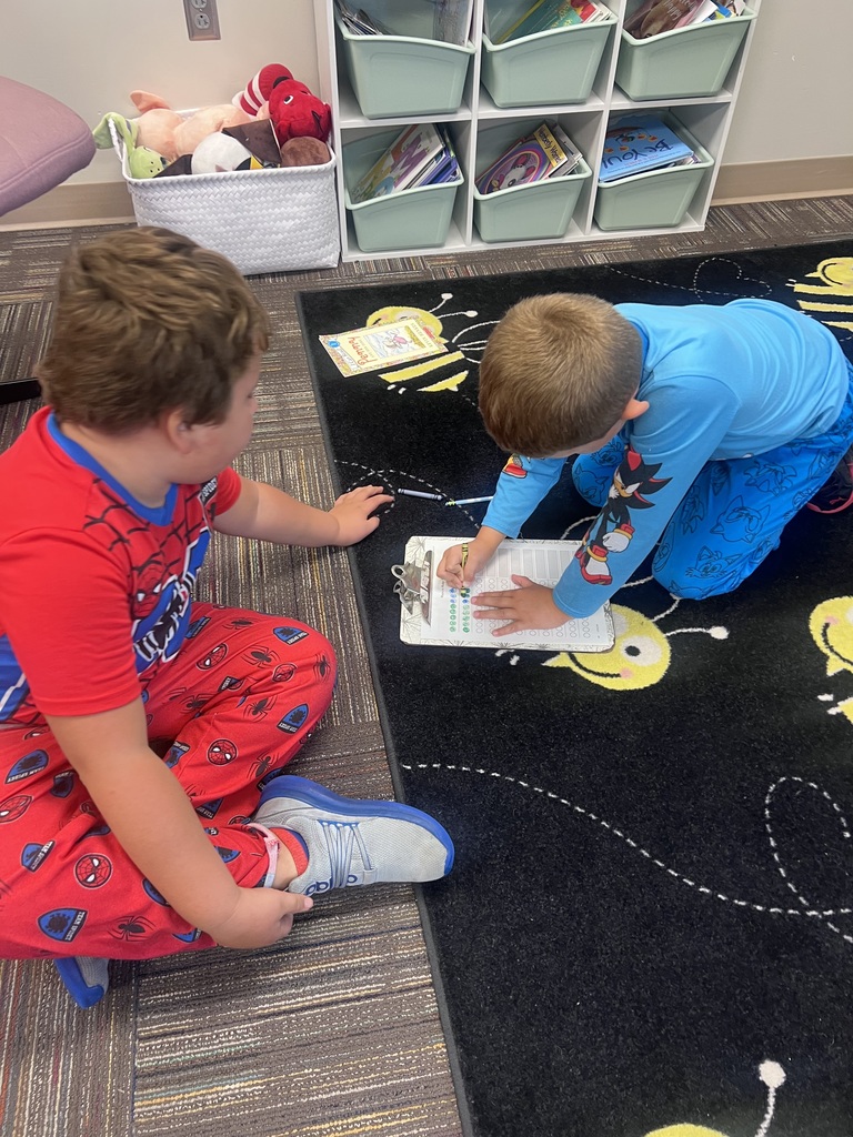 two students with a clipboard laying on the floor doing math