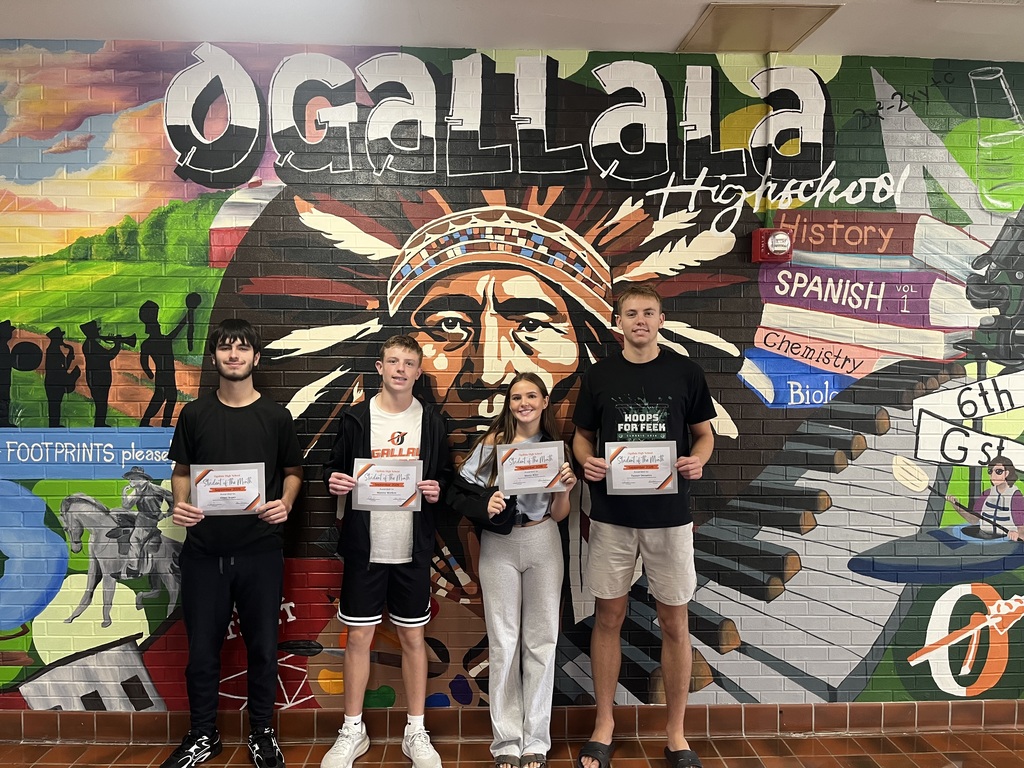 student of the month standing with paper in front of indian mural
