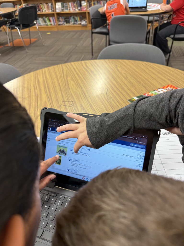 students pointing to s screen with a picture of a book about spiders
