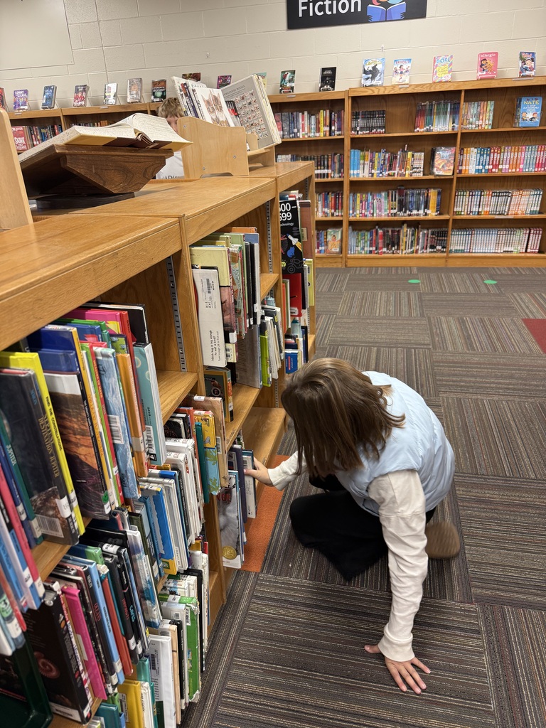 students looking at a book shelf full of books