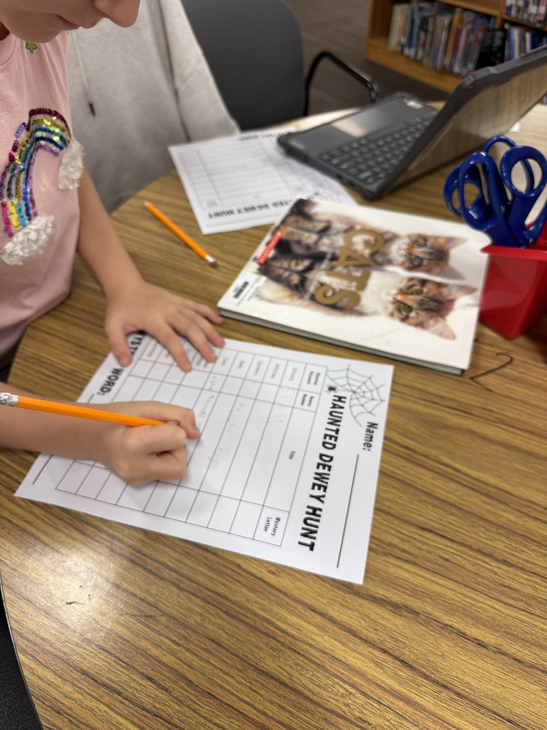 students writing on a paper with a cat book sitting on the table