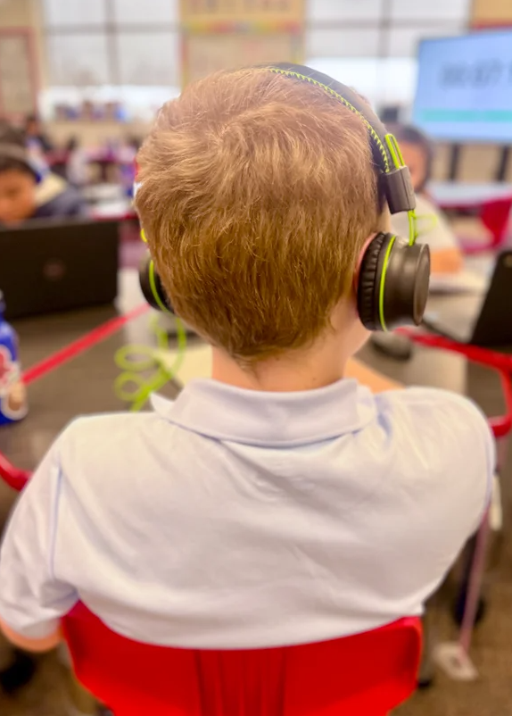 elementary student wearing headphones at desk