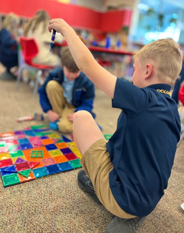 elementary students sitting on floor with colorful blocks