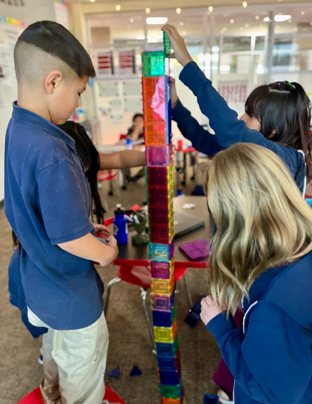 elementary students working with colorful blocks at classroom table