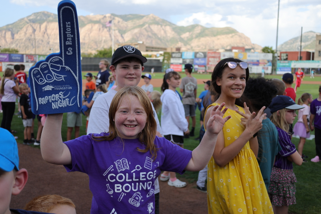 elementary students holding foam finger on baseball field
