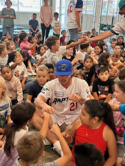 Raptors player sitting in group of students