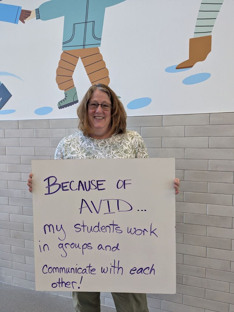 Teacher holding a whiteboard with an explanation of why they love AVID