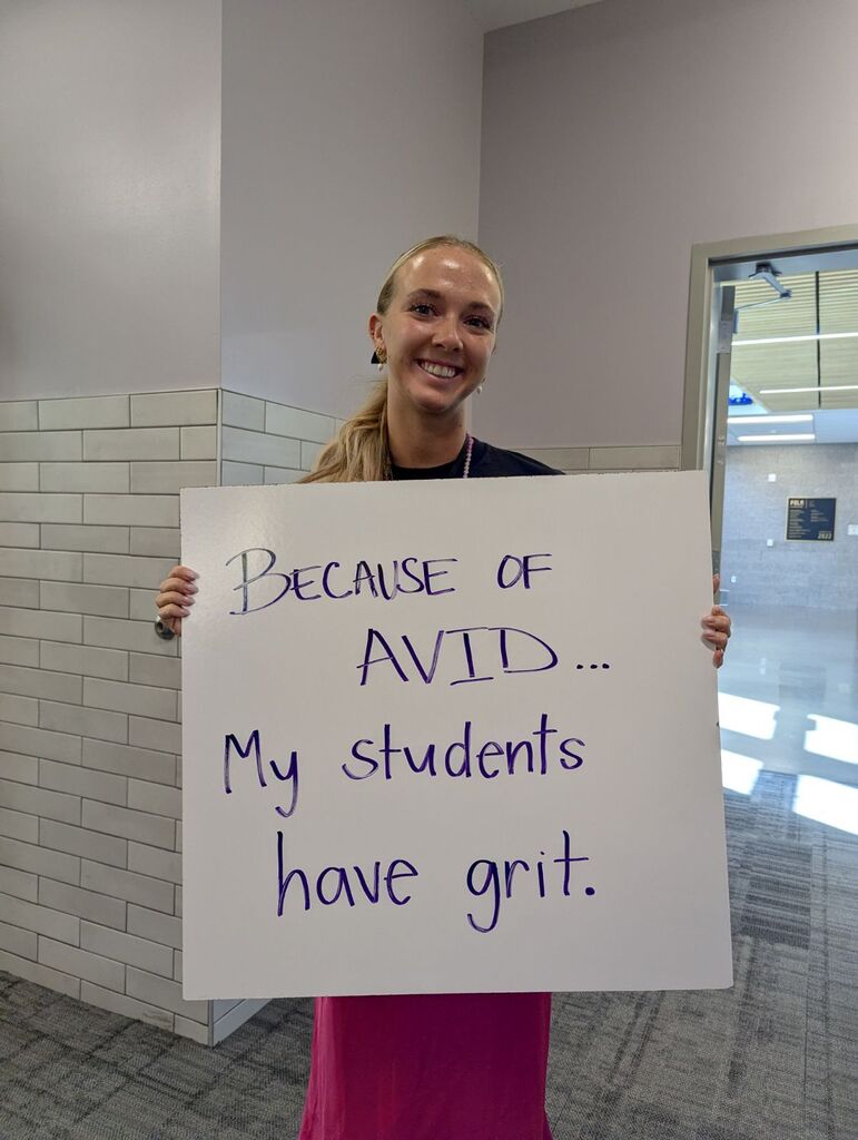 Teacher holding a white board explaining why they love AVID