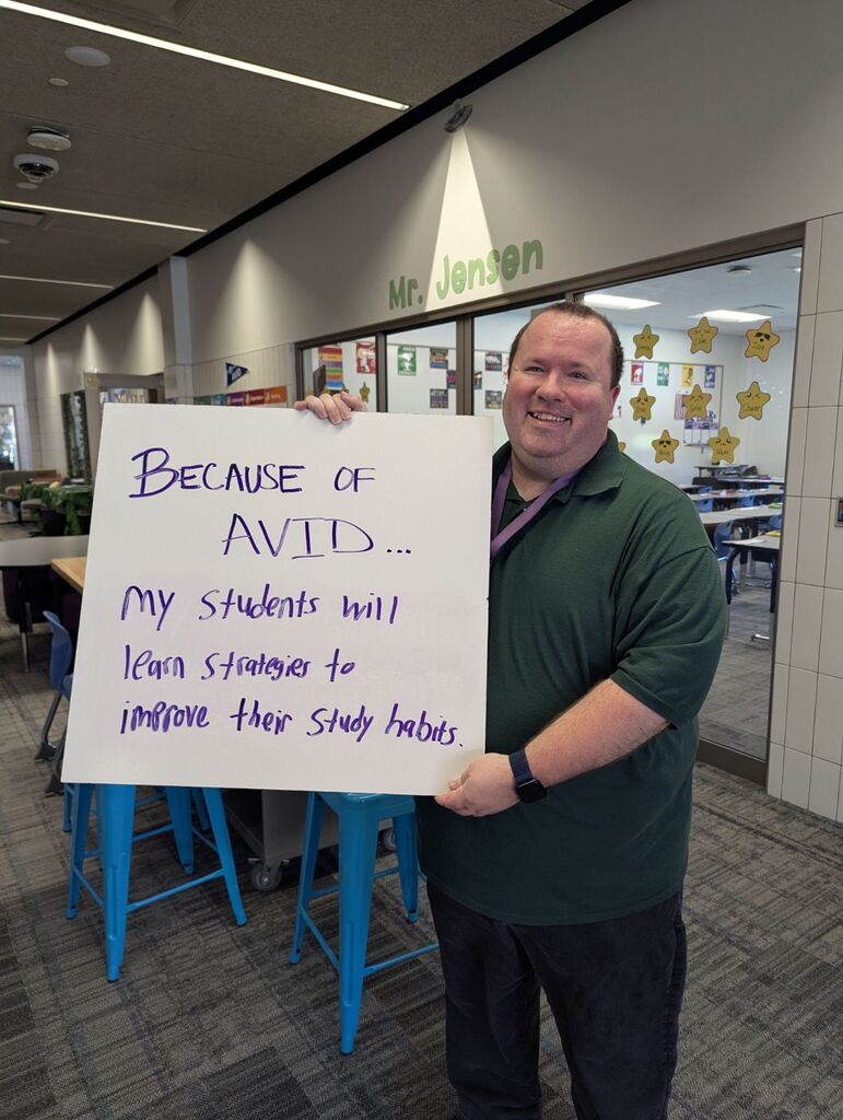 Teacher holding a whiteboard with an explanation of why they love AVID