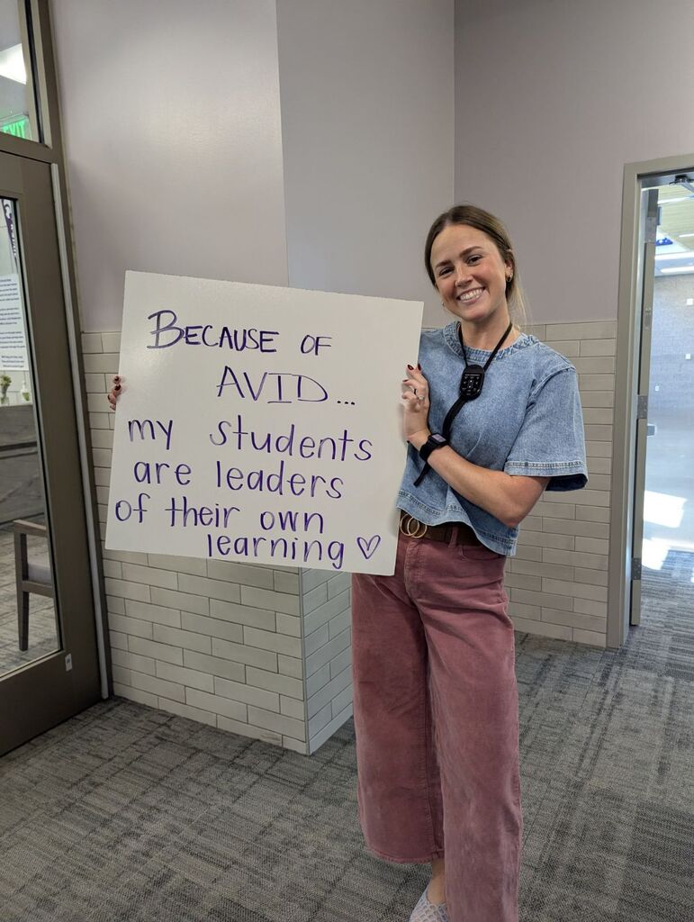Teacher holding a whiteboard with an explanation of why they love AVID