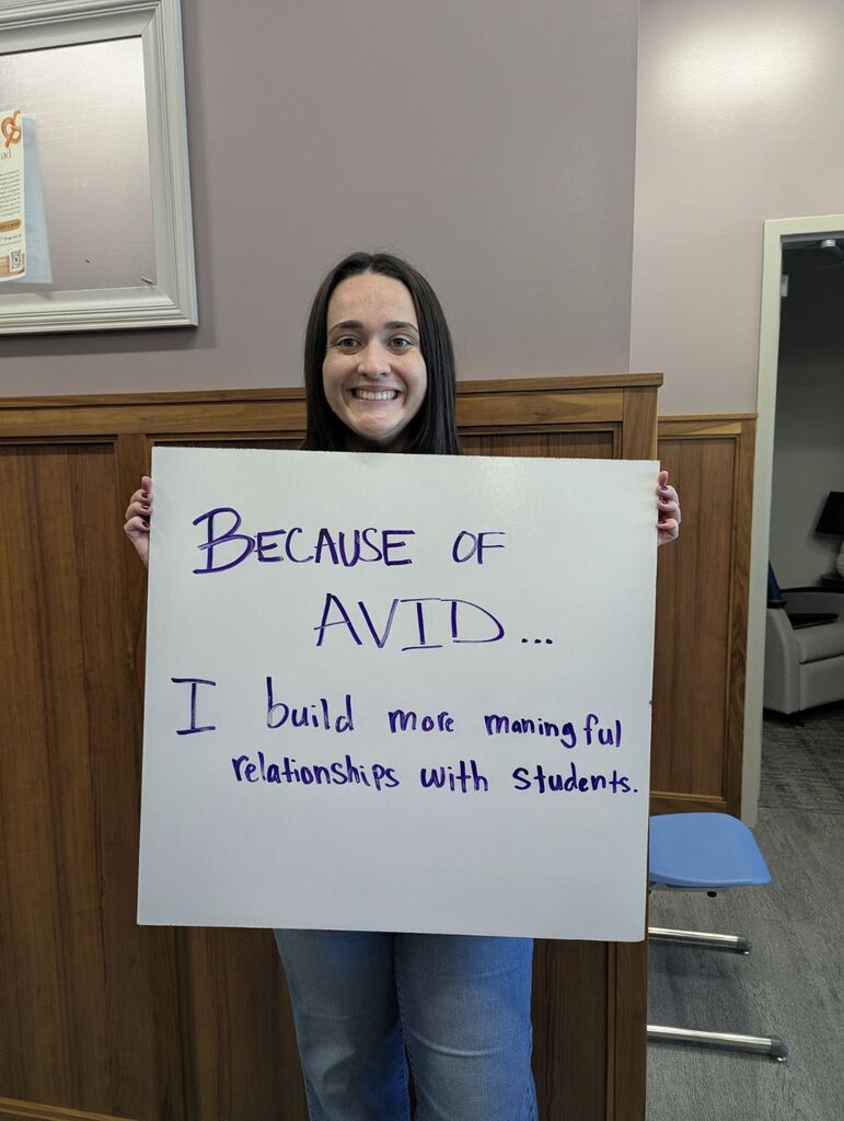 Teacher holding a whiteboard with an explanation of why they love AVID