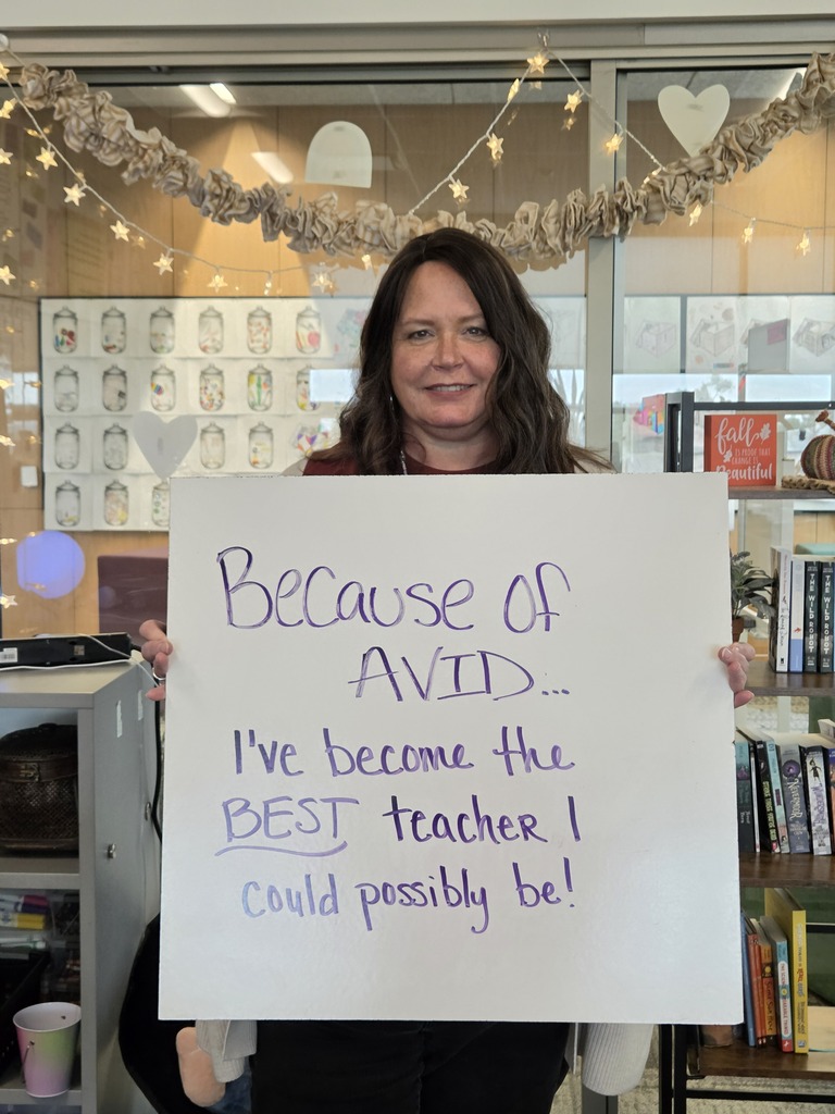 Teacher holding a whiteboard with an explanation of why they love AVID