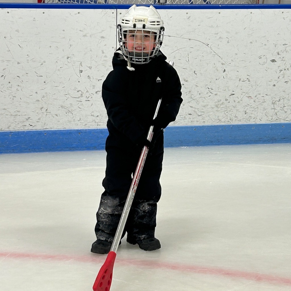 A student with a hockey helmet on and a stick 