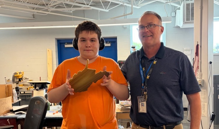 child posing with WV cutting board and teacher
