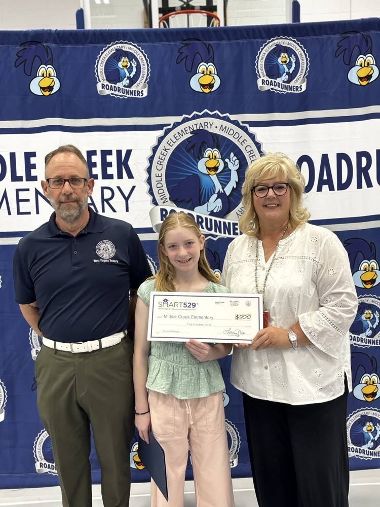 two adults posing with child holding a check 
