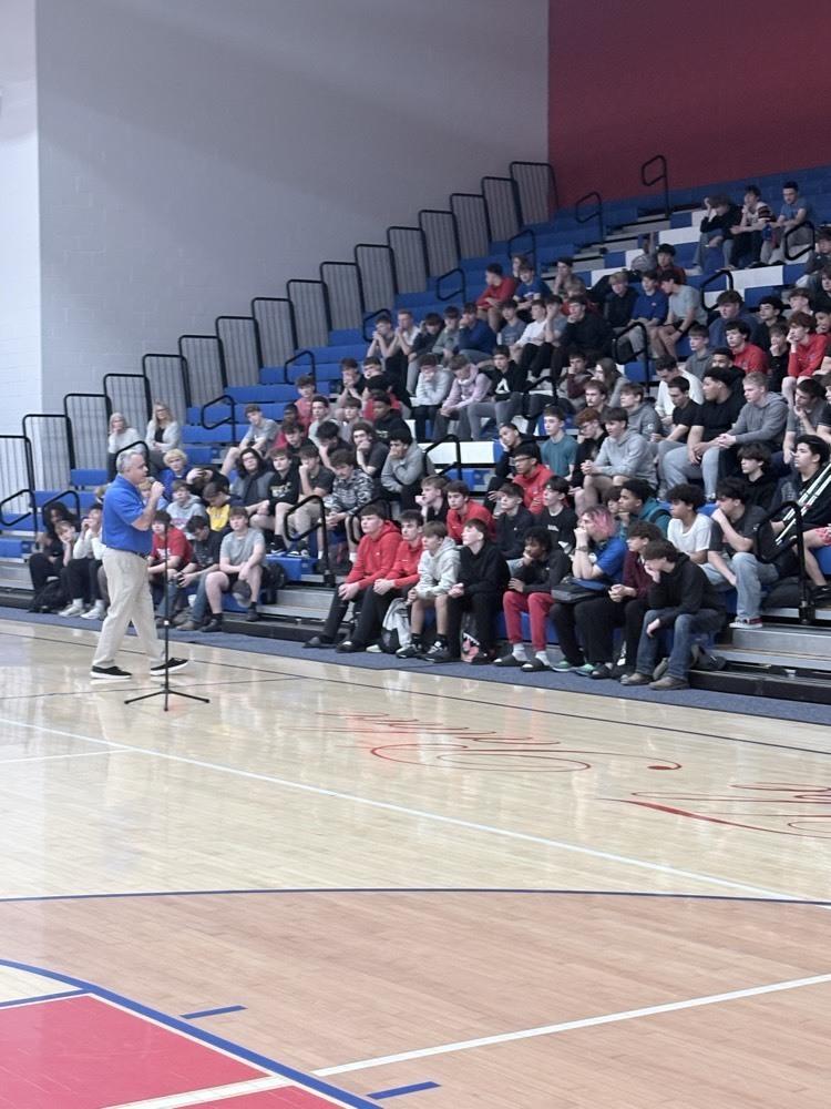 student body sitting in bleachers listening to adult talk 