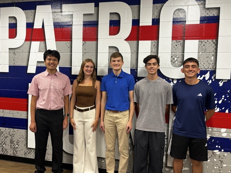 students posing in front of Patriot sign