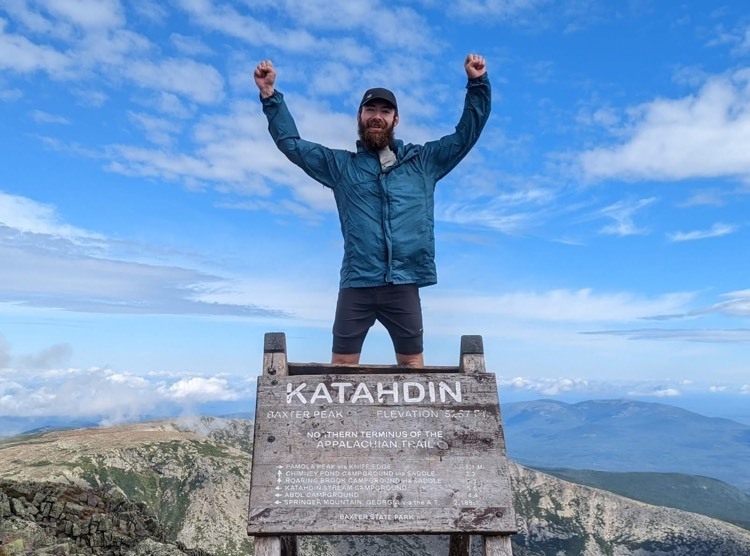 man posing with his arms raised in victory after hiking 