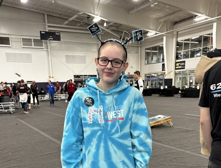 girl in blue sweatshirt and headband smiling 