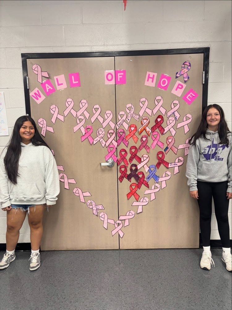 students posing next to pink ribbons