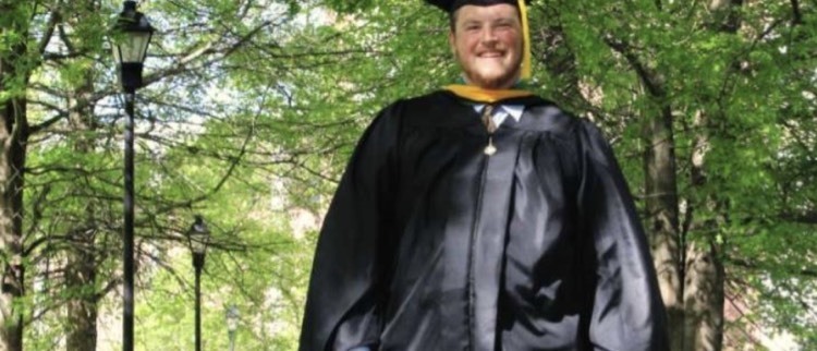 man in graduation gown walking dog 