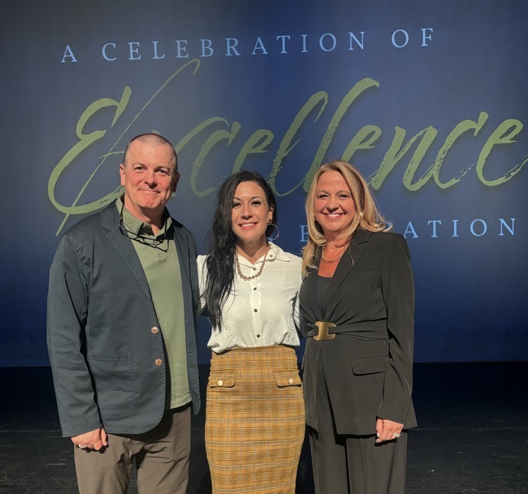 teacher posing in between the assistant superintendent and superintendent