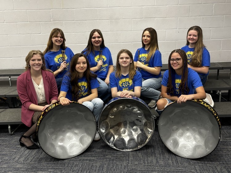 girls posing with steel band drums