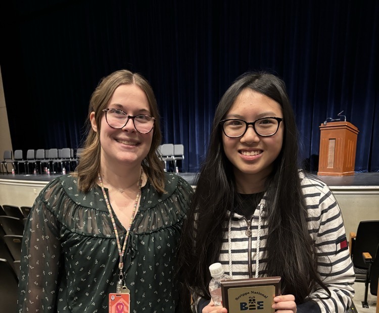 a teacher and student posing with spelling bee plaque