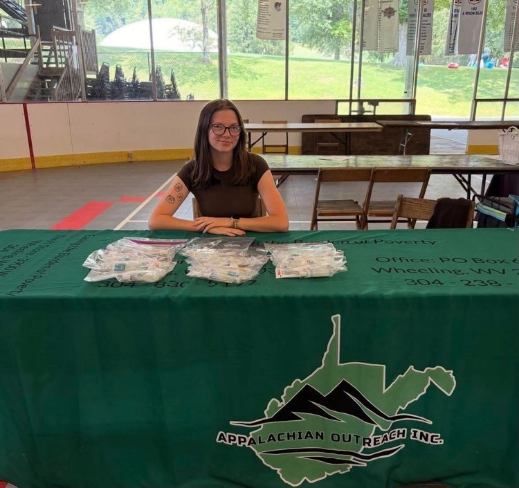 woman posing at table and smiling representing Appalachian Outreach