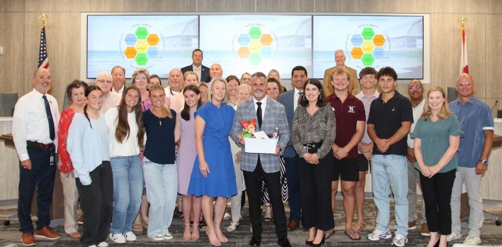 Charlie Marello and his family pictured with friends, coworkers, and School Board members at School Board meeting.