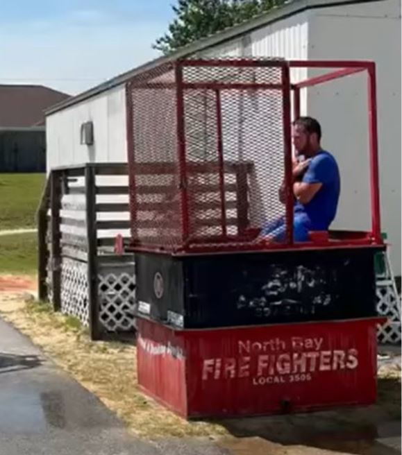 Coach sitting in dunk in red dunk tank