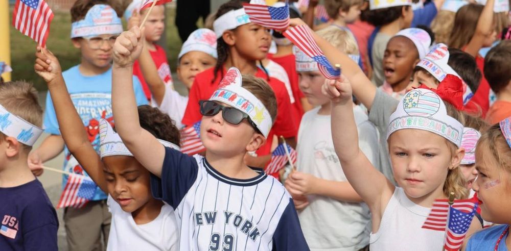 Purple Star Schools - elementary students waving American flags.