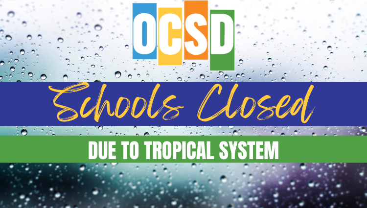 Graphic with the colorful OCSD logo over a background of raindrops on glass. A dark blue banner reads “Schools Closed” in yellow script, with a green banner below stating “DUE TO TROPICAL SYSTEM” in white capital letters.