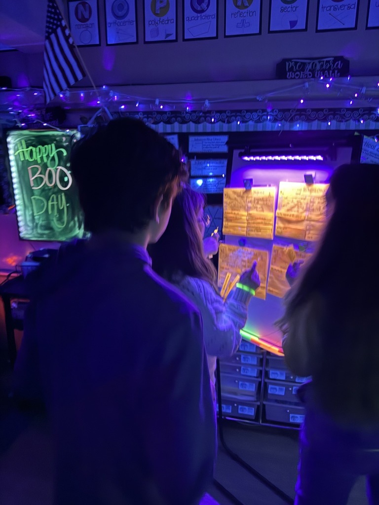 Student's working on math problems under neon-lights. Karmen Broaddus’s classroom at Ruckel Middle School with a spine-tingling twist on math! Students dove into a neon-themed learning experience.