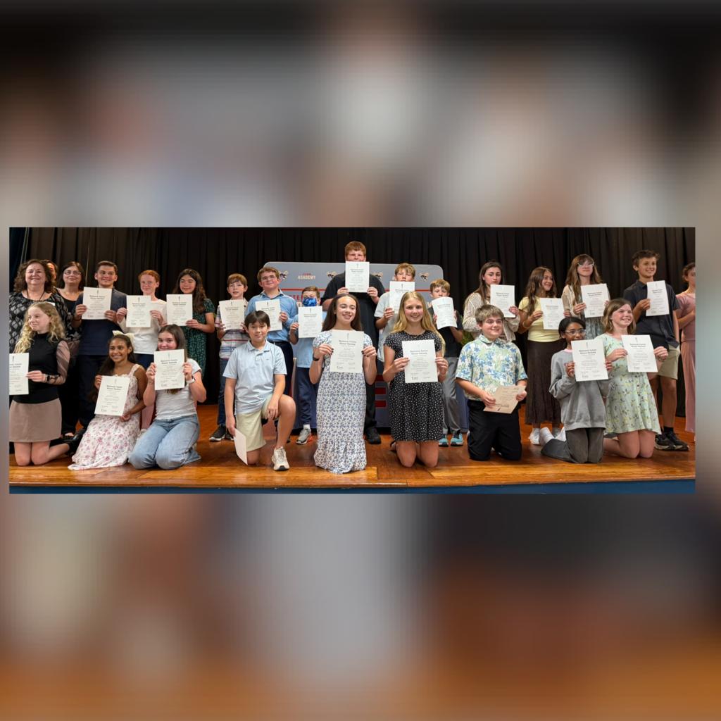 Photo of new NJHS inductees standing on the stage holding their certificates. 