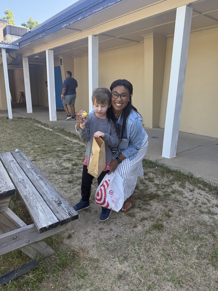 A teacher posing for picture with  a student during an egg hunt activity on campus