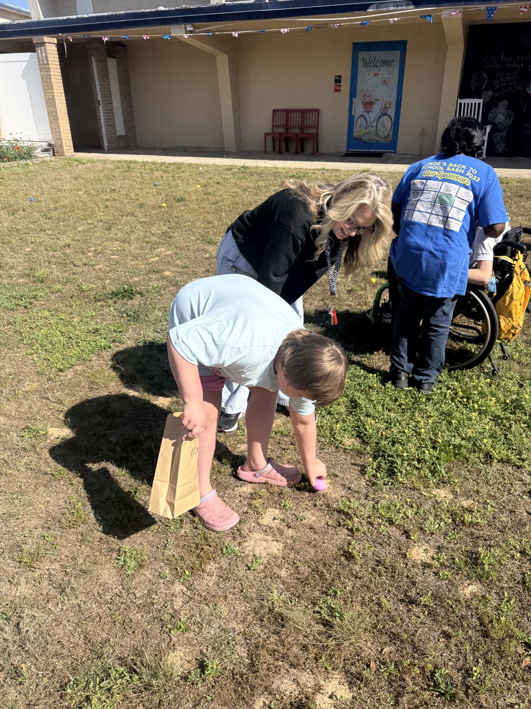 A teacher assisting a student during an egg hunt activity at Richburg. 