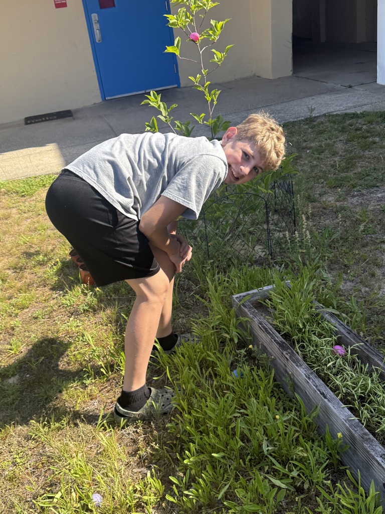 A student smiling while finding a plastic egg during the school egg hunt.