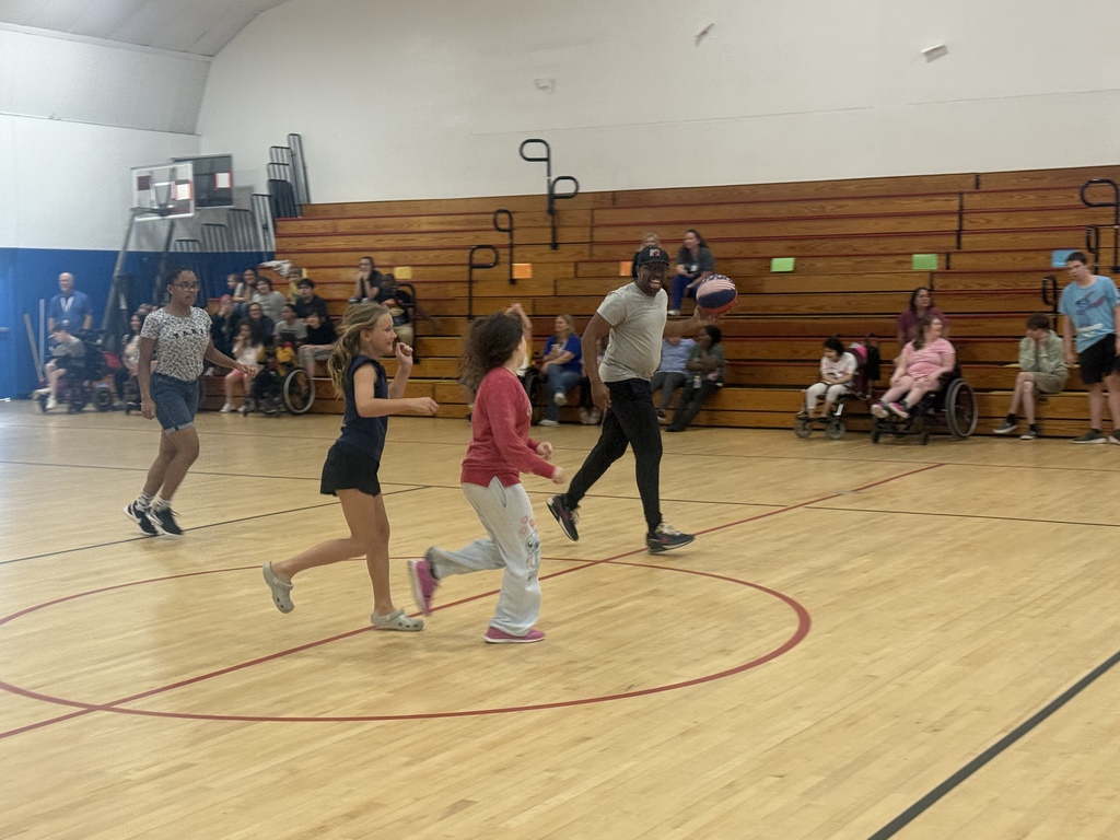 Students run down the basketball court during the annual basketball game while classmates watch from the bleachers.