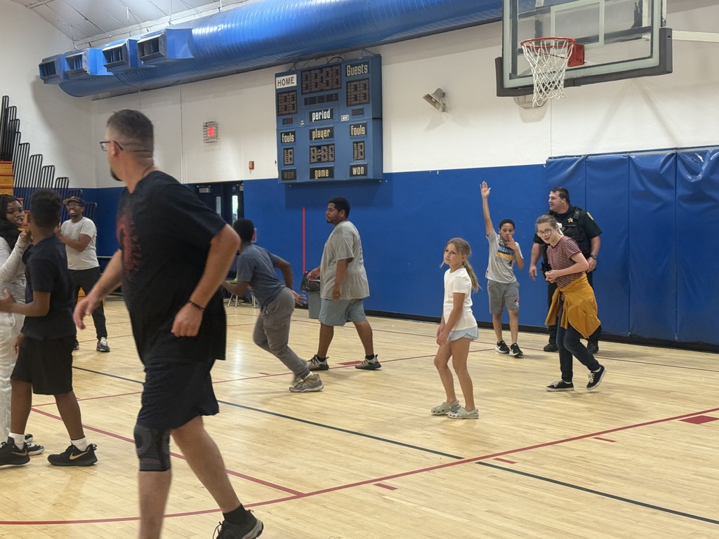 Students, staff, and school resource officers play basketball together in the school gym.