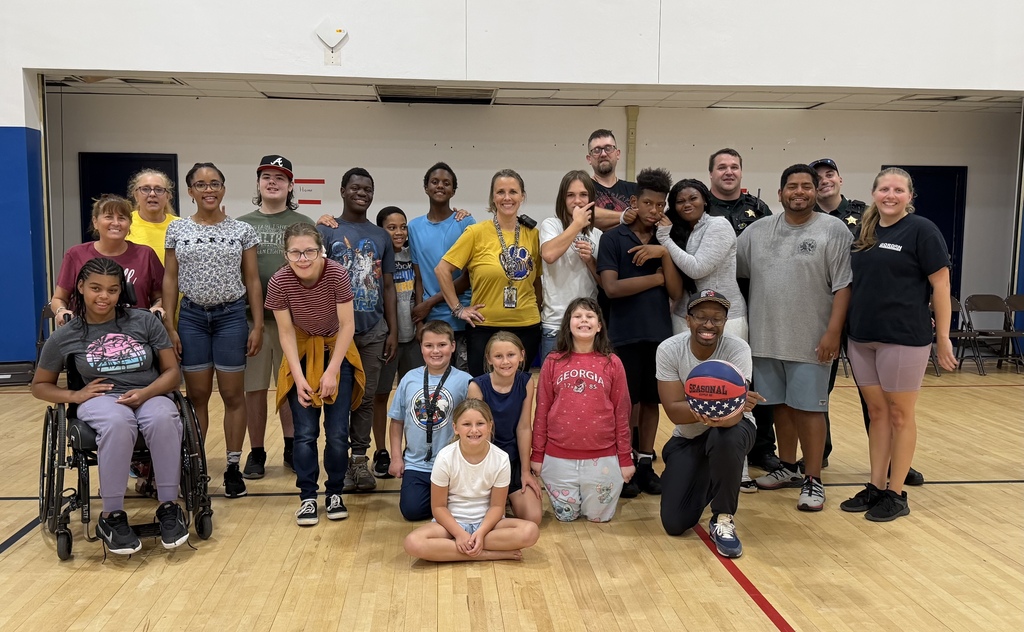 Group photo of Richbourg students, staff members, and school resource officers gathered together in the gym after the annual basketball game.