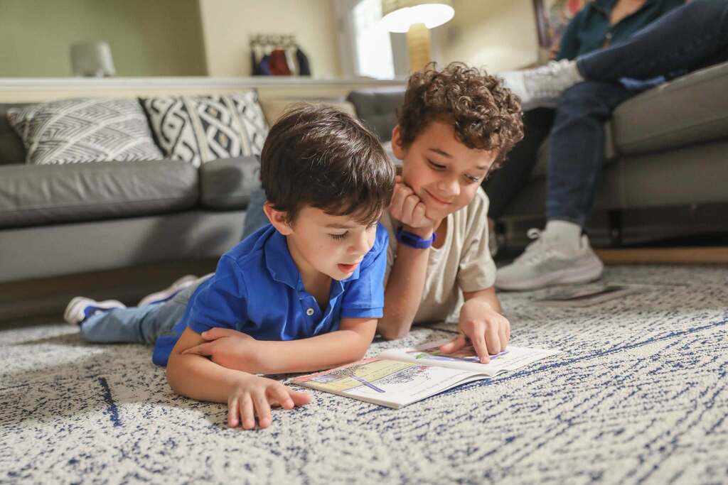 2 young boys reading on floor at home