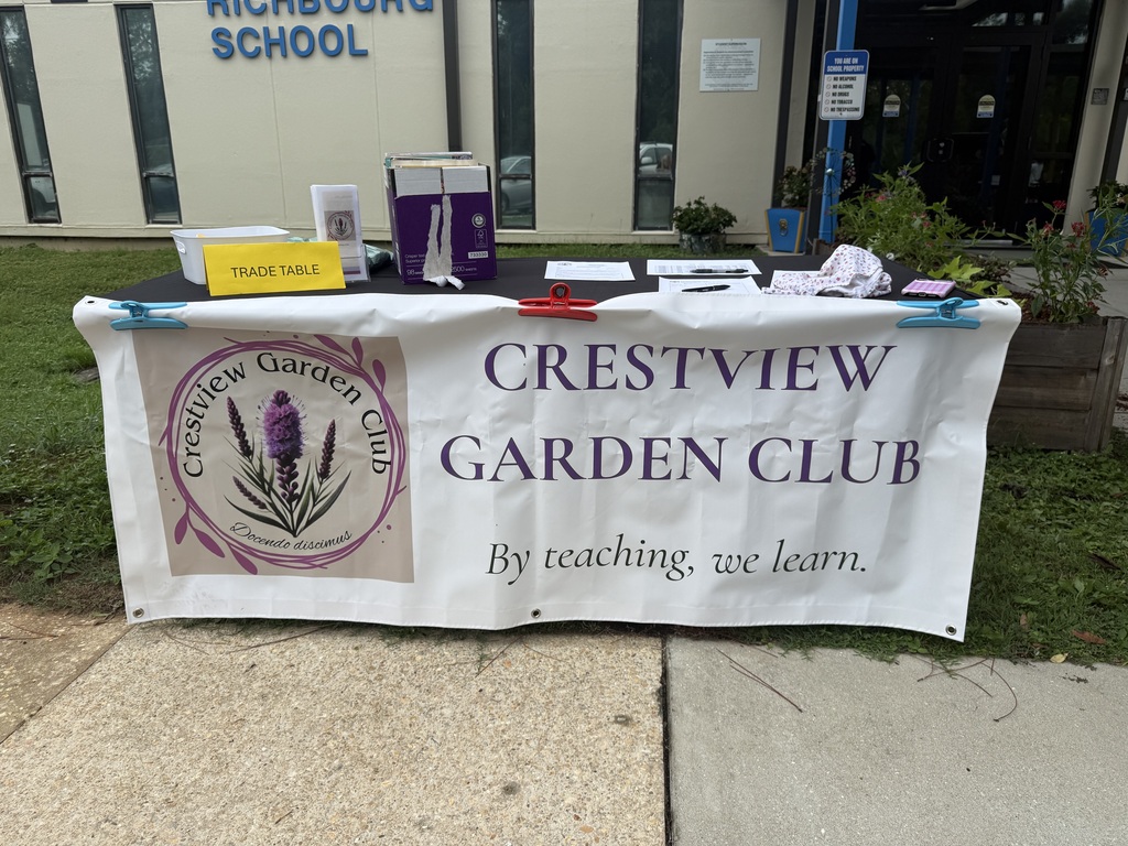Crestview Garden Club display table set up outside Richbourg School with a large Garden Club banner and gardening materials