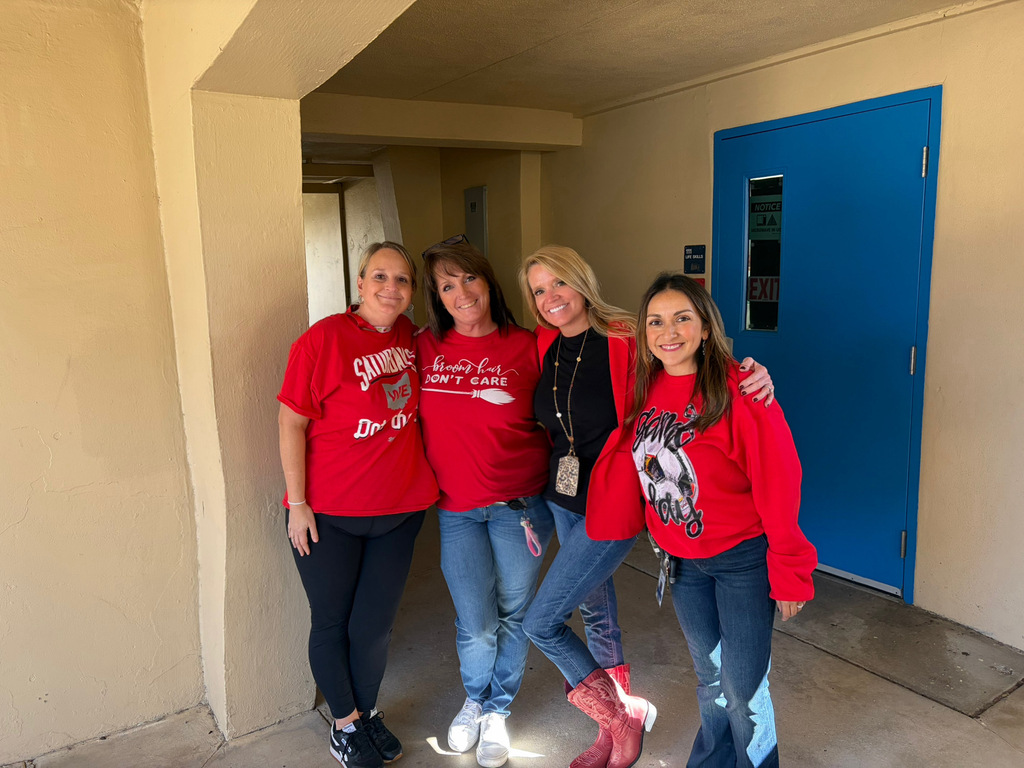 Four staff members dressed in red pose together outside a classroom during Red Ribbon Spirit Day, celebrating school spirit and healthy, drug-free choices